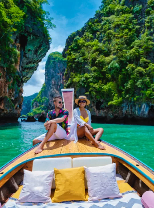 Man en vrouw op de punt van een long tail boat op het water in Thailand