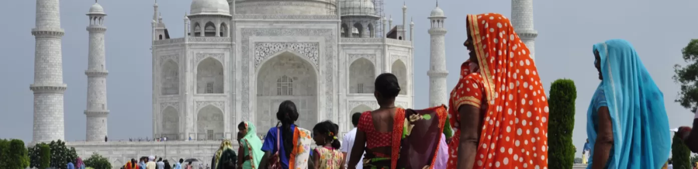 Achteraanzicht van dames die in kleurrijke, traditionele kleding richting de Taj Mahal lopen.